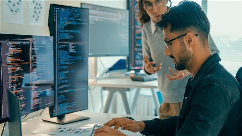Photo of people with computer screens in the background